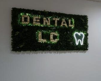 Mujer sonriente con bata de laboratorio y equipo, con los brazos cruzados. Entorno médico.