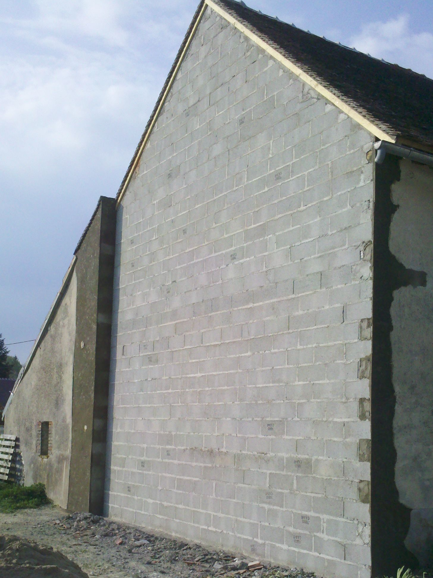 Un mur en parpaings collé à un autre mur à côté d'un chemin
