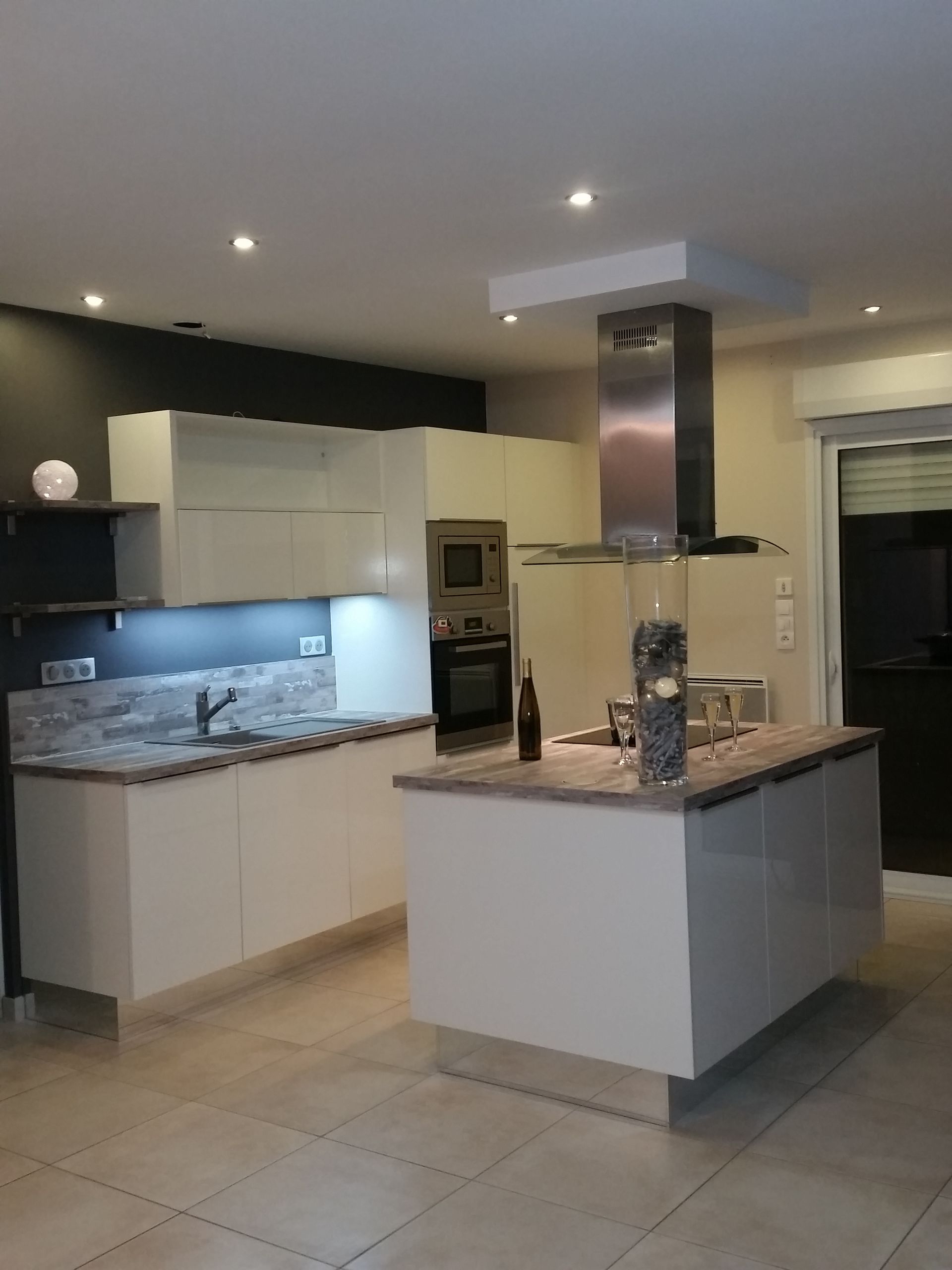 Cuisine moderne avec un îlot central, une hotte en acier inoxydable et des comptoirs.