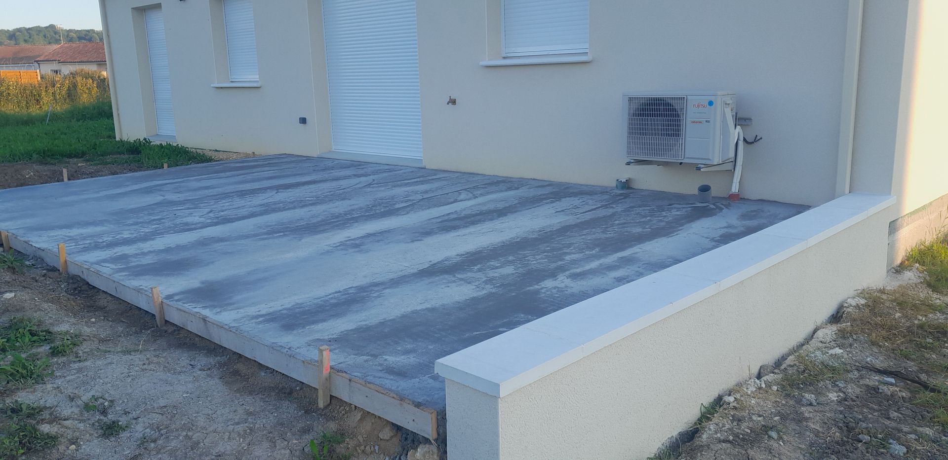 Construction d'une maison avec dalle de terrasse, coffrages en bois, briques empilées et une maison avec de grandes portes vitrées
