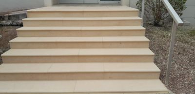Un escalier extérieur mène à un porche avec une rambarde blanche