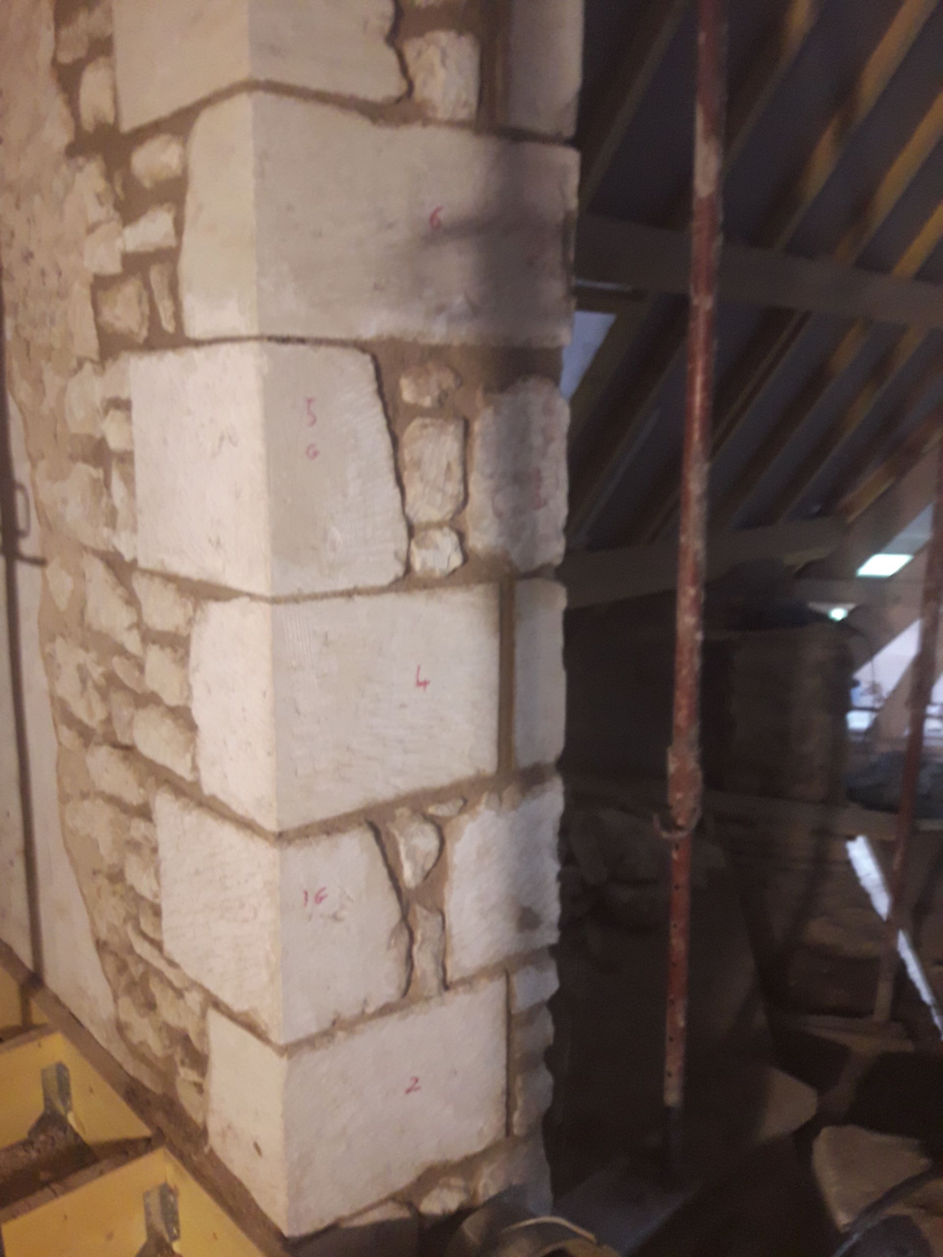 Mur et colonne en pierre dans un grenier, avec des poutres en bois apparentes