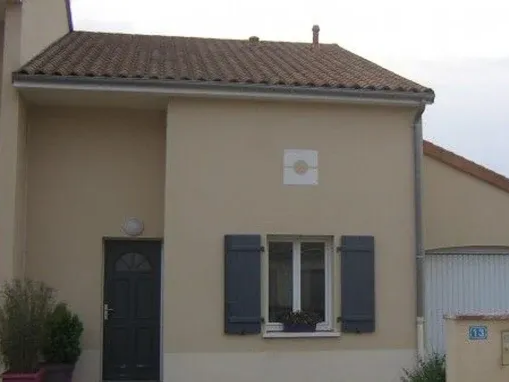 Petite maison avec des volets foncés et une porte d'entrée