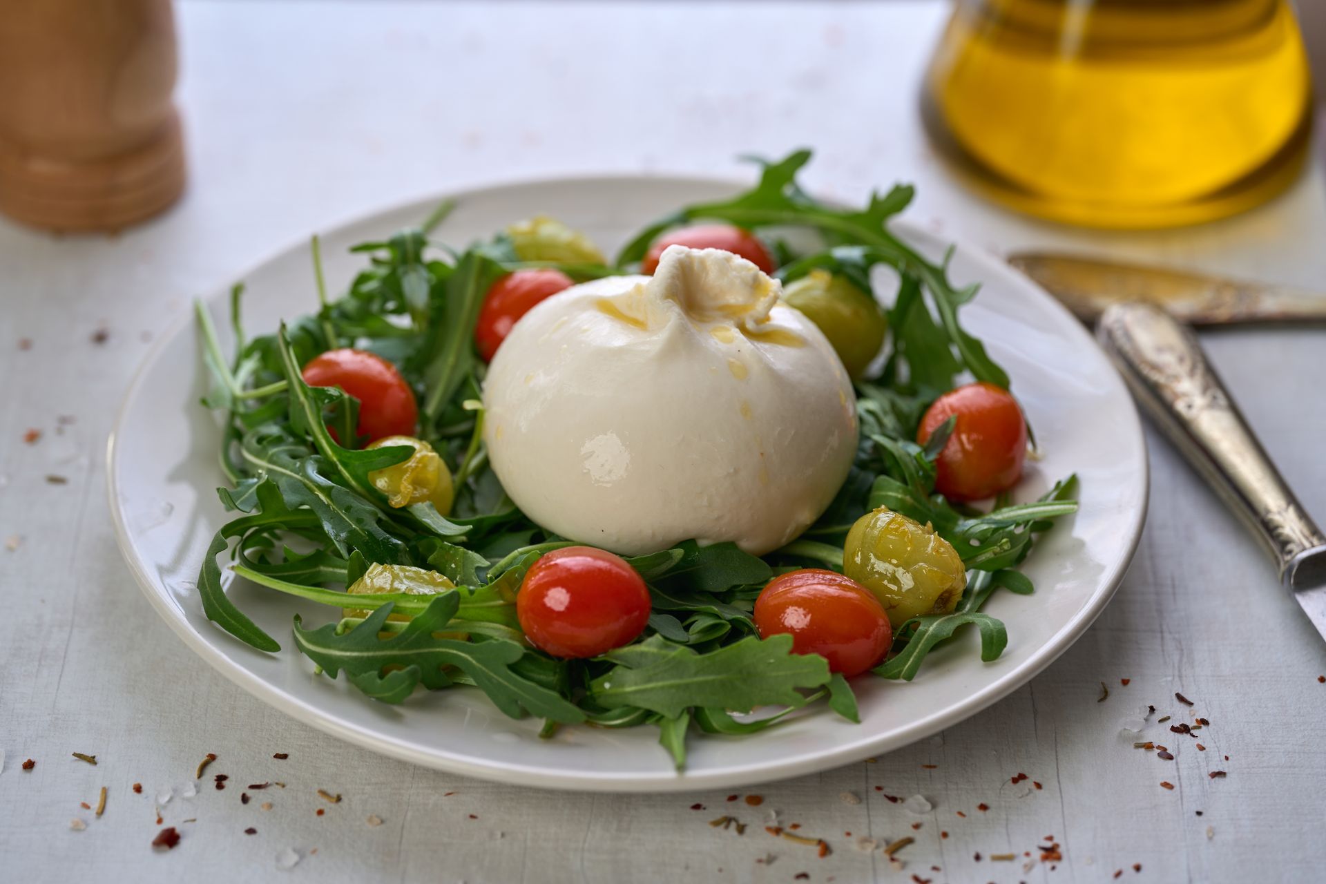 Queso burrata sobre cama de rúcula con tomates cherry.