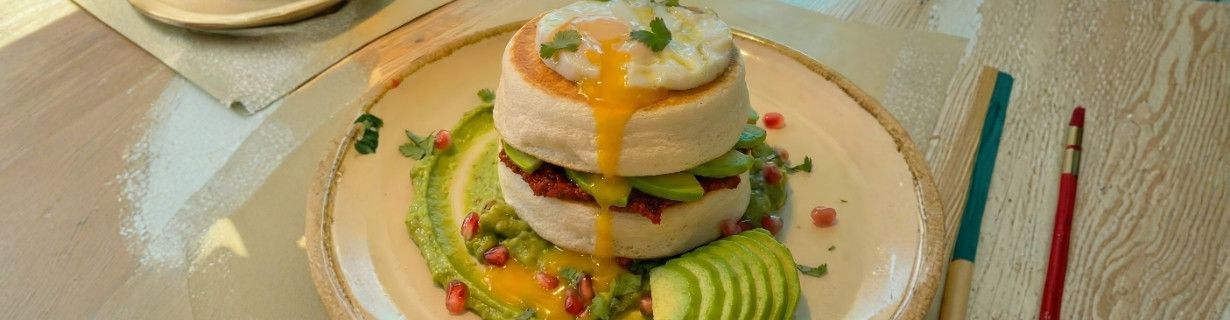 Ramekin rojo con huevos horneados, prosciutto y una guarnición de papas fritas.