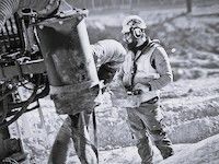 Rakennustyöntekijät valavat betonia mutaisella työmaalla raskaiden koneiden vieressä