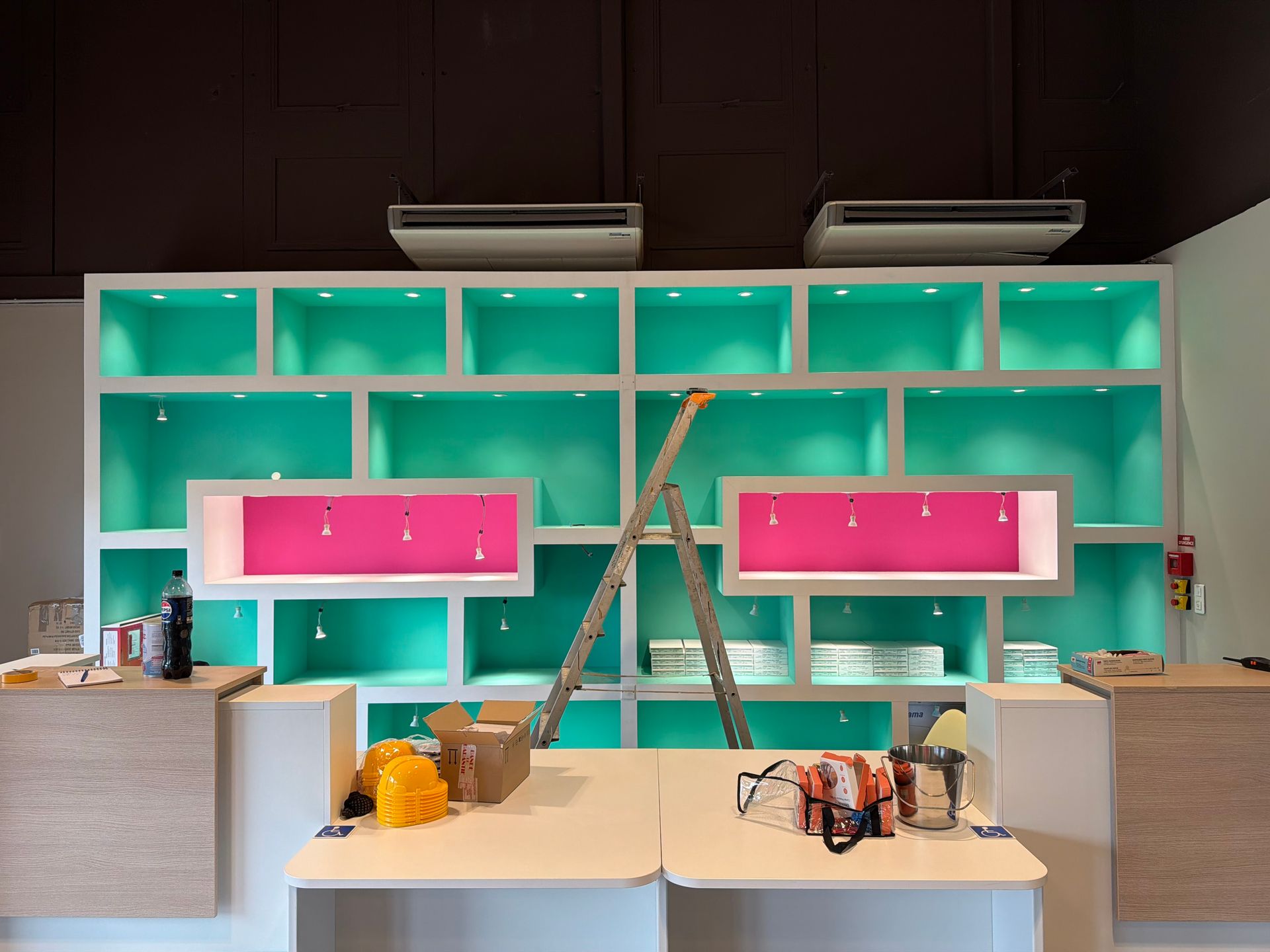 Intérieur coloré d'un magasin avec des étagères turquoise, des panneaux d'affichage roses et des tables présentant des outils et des fournitures.