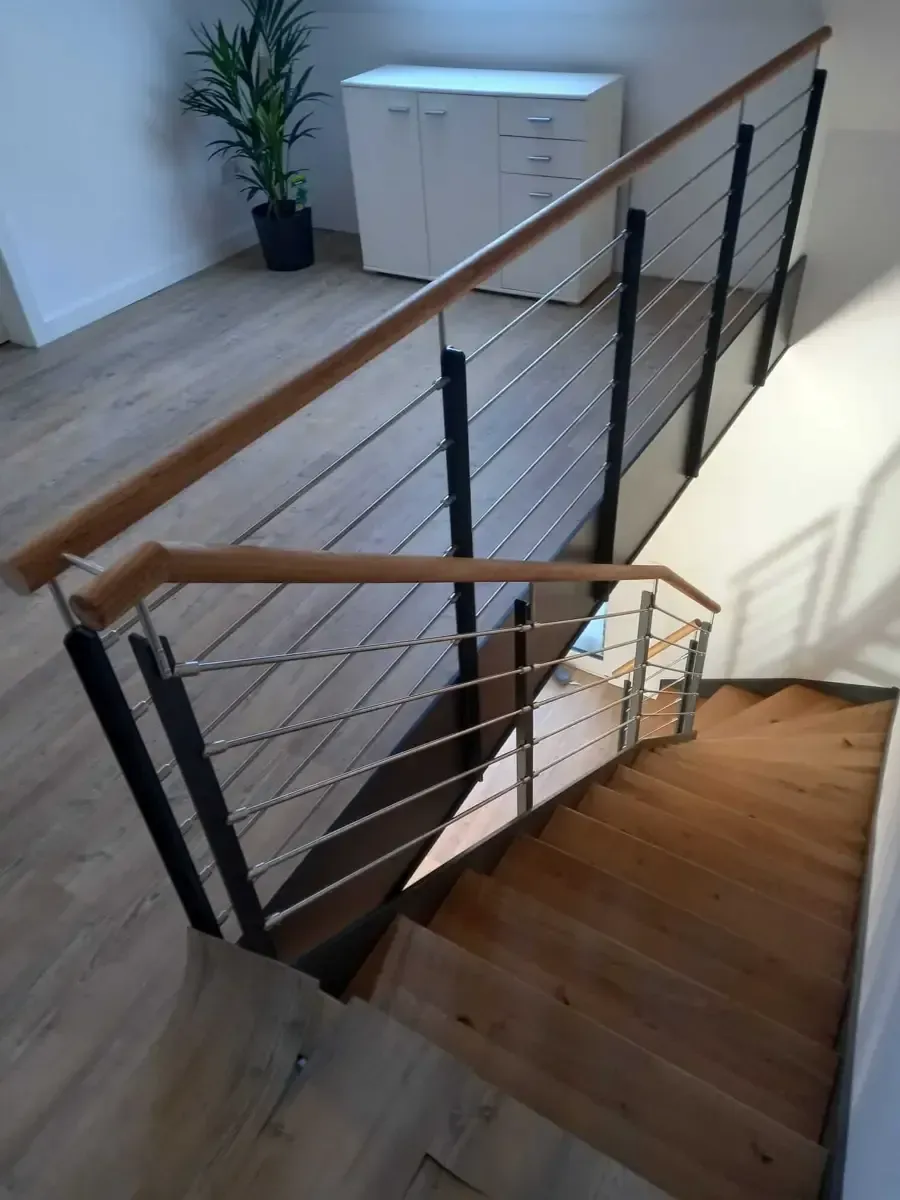 Blick von oben auf eine Holztreppe mit modernem Geländer