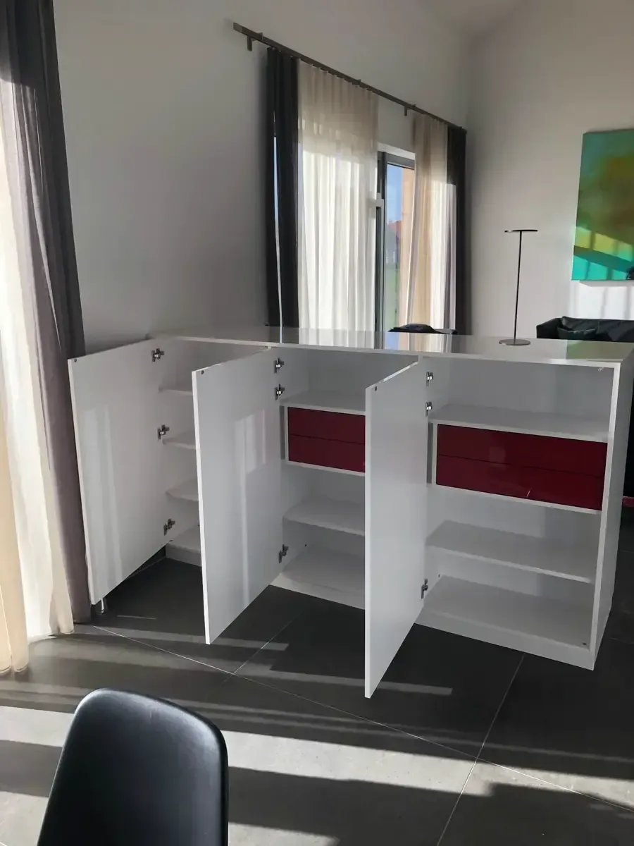 In einem hellen, modernen Zimmer steht in der Nähe eines Fensters ein weißer Schrank