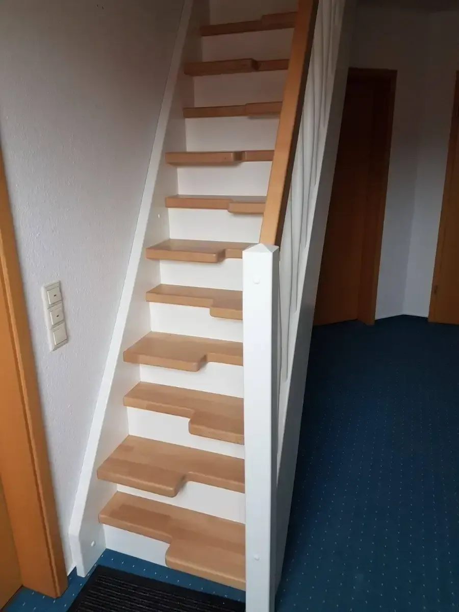 Steile Holztreppe mit abwechselnden, schaufelförmigen Trittstufen