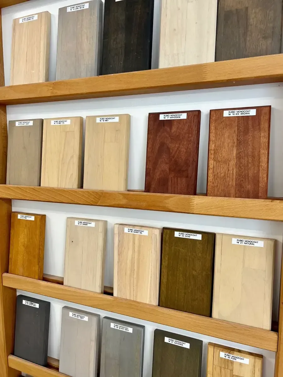Ein hölzernes Ausstellungsregal mit mehreren kleinen, rechteckigen Holzbeizmusterplatten