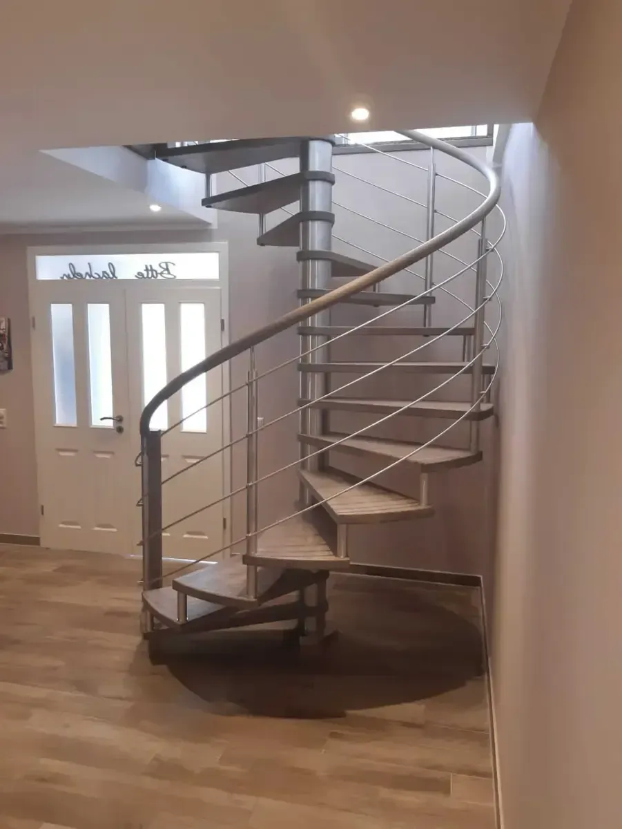 Eine Wendeltreppe mit hellen Holzstufen und einem eleganten Metallgelände