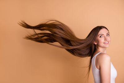 Una mujer sostiene una pastilla en su mano y mira su cabello.