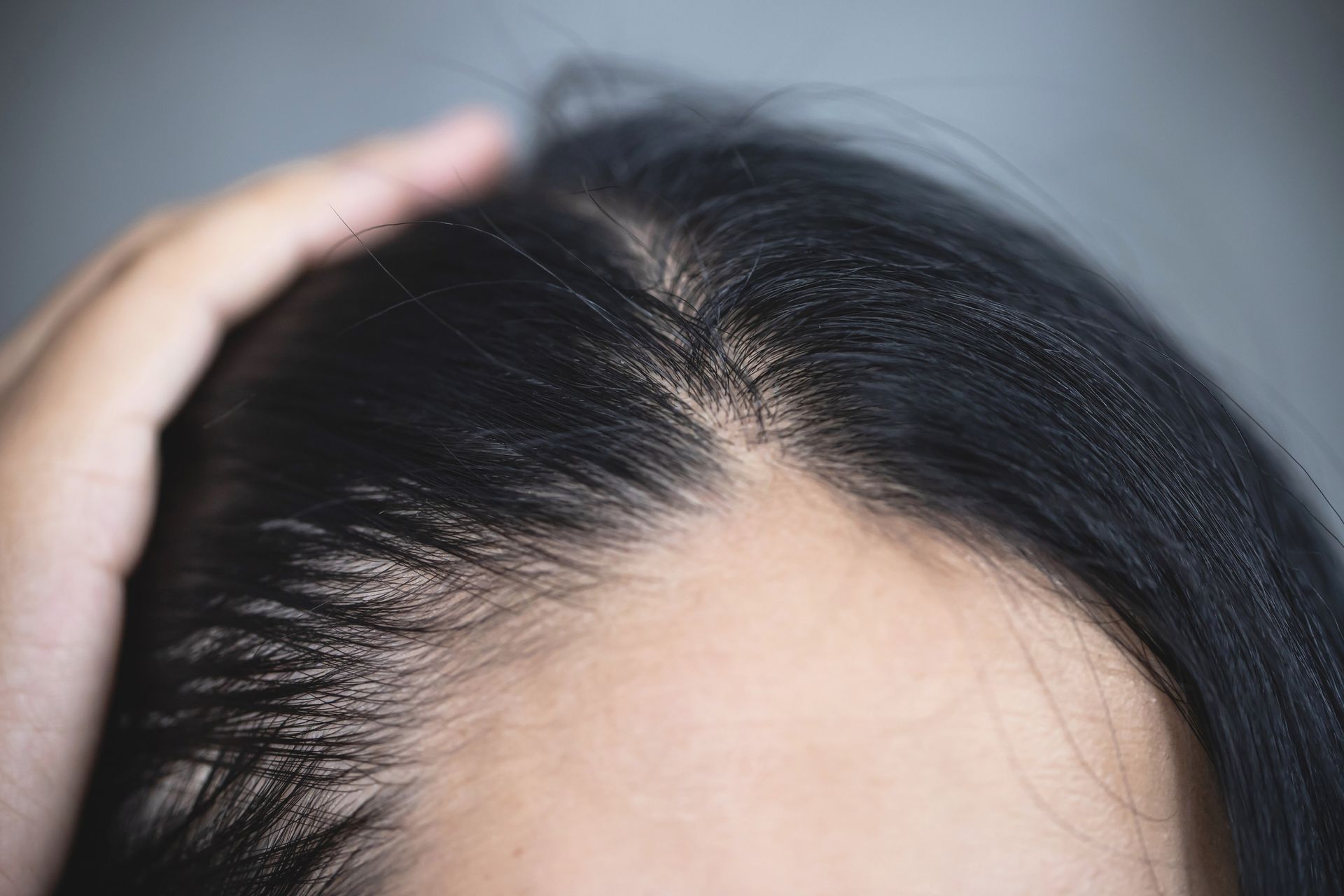 Un primer plano de la cabeza de una mujer con su mano en su cabello.