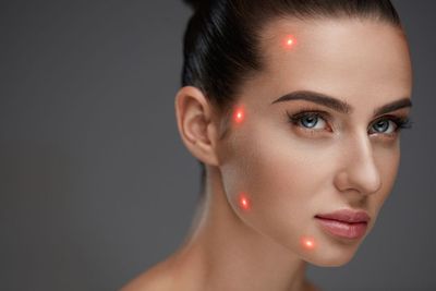 Un primer plano del rostro de una mujer con luces rojas en él.