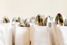 Una fila de bolsas blancas llenas de cubiertos sobre una mesa.