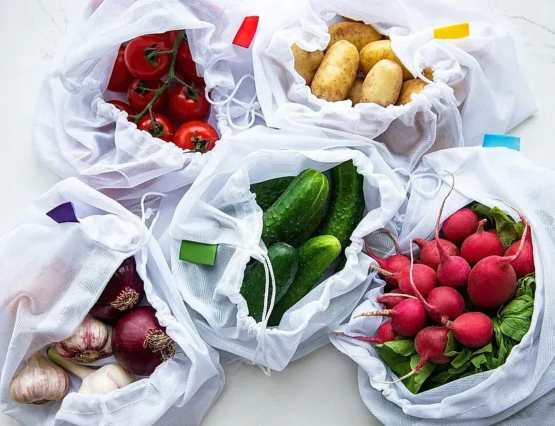 Un montón de bolsas llenas de verduras sobre una mesa.
