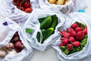 Un montón de bolsas llenas de verduras sobre una mesa.