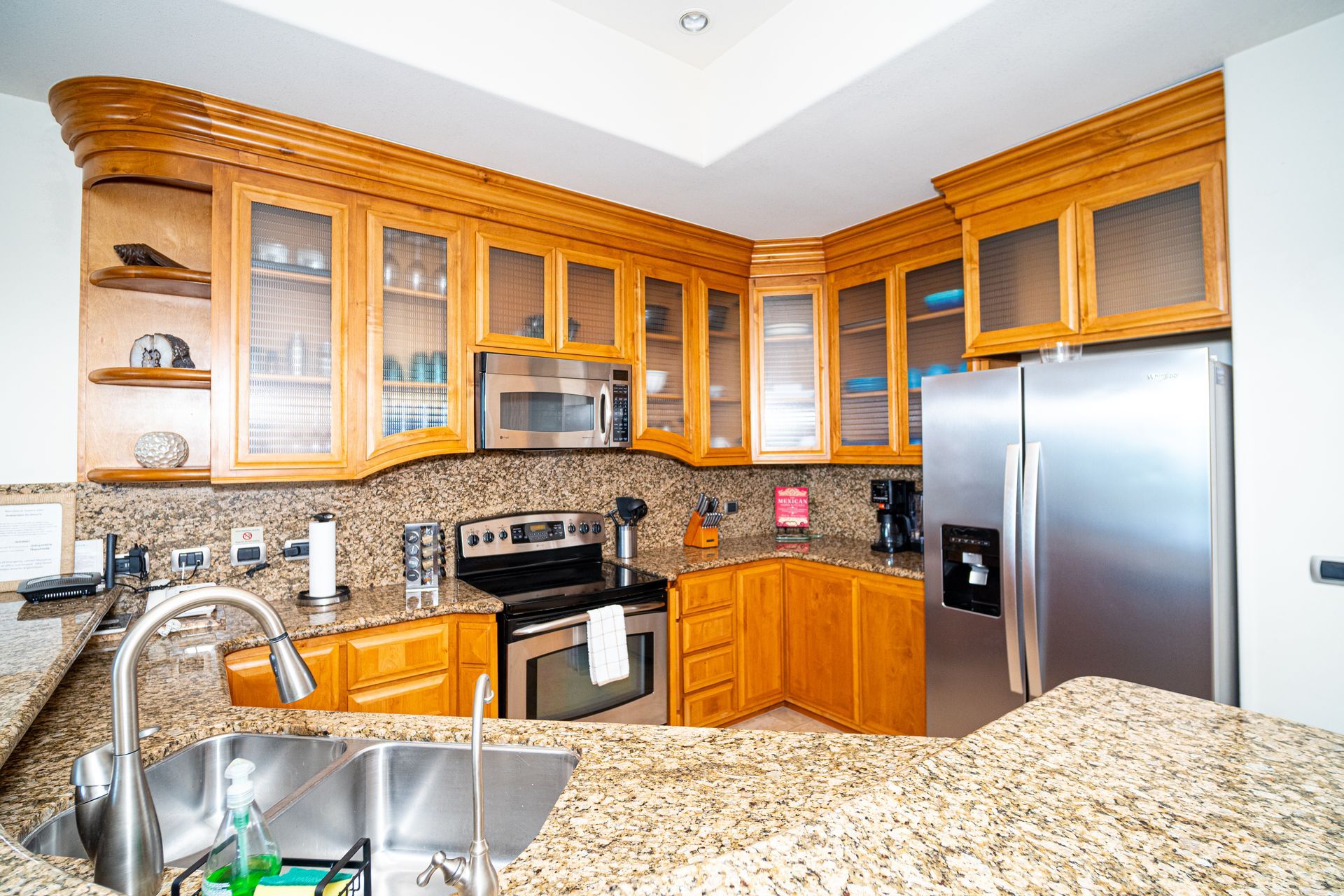 Bright kitchen with wood cabinets, granite counters, stainless appliances, and a double sink