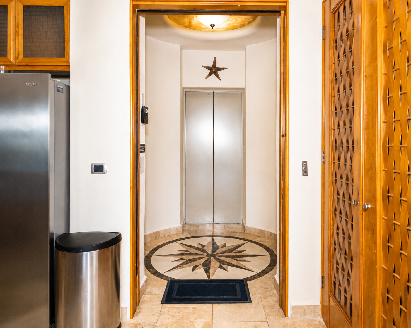 Elevator doors in a bright hallway with a compass star mosaic on the floor