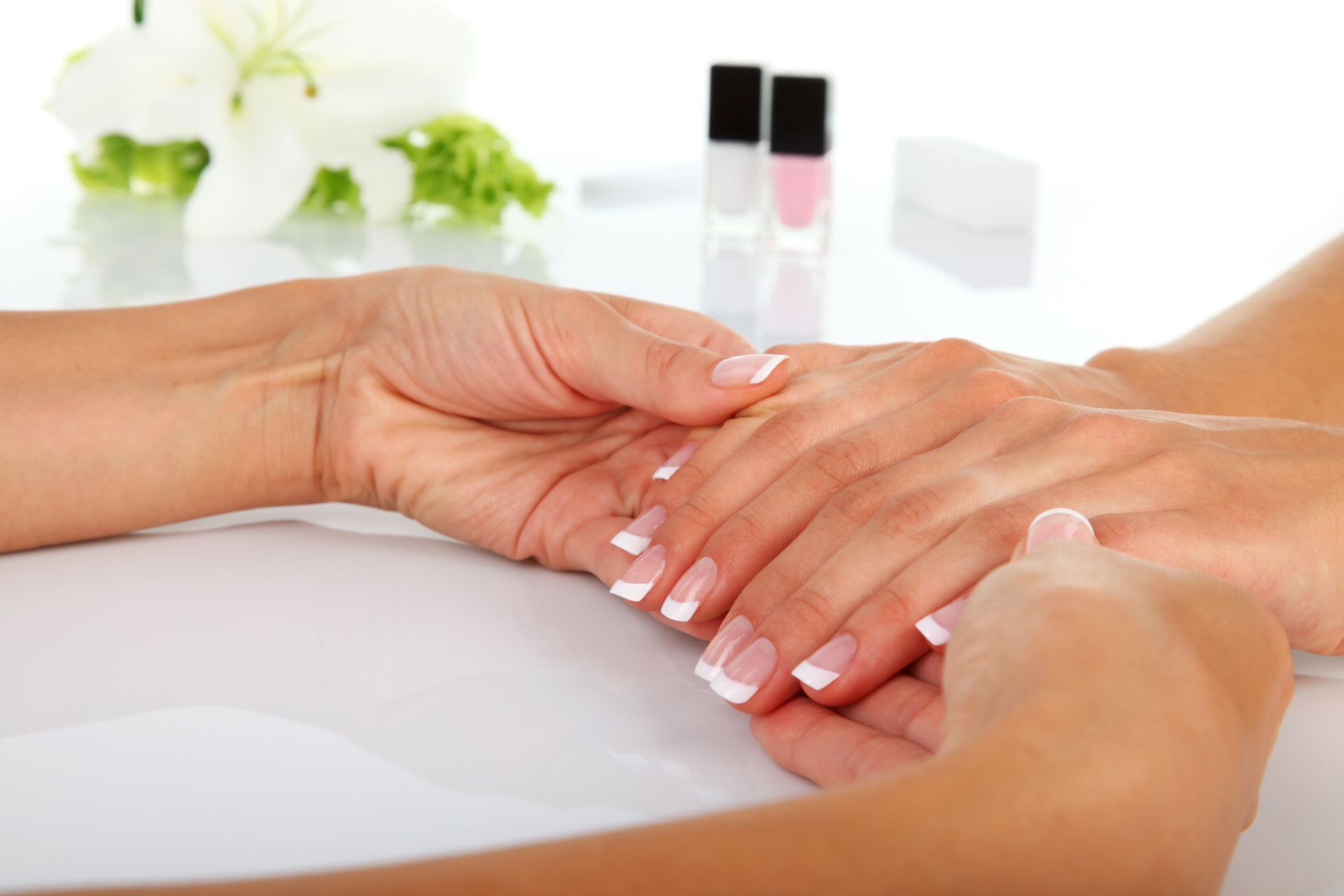 Hände mit französischer Maniküre erhalten eine Handmassage in einem Spa.