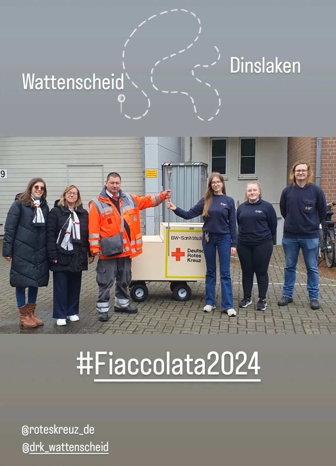 Eine Gruppe von Menschen steht neben einem Wagen mit einem roten Kreuz darauf.