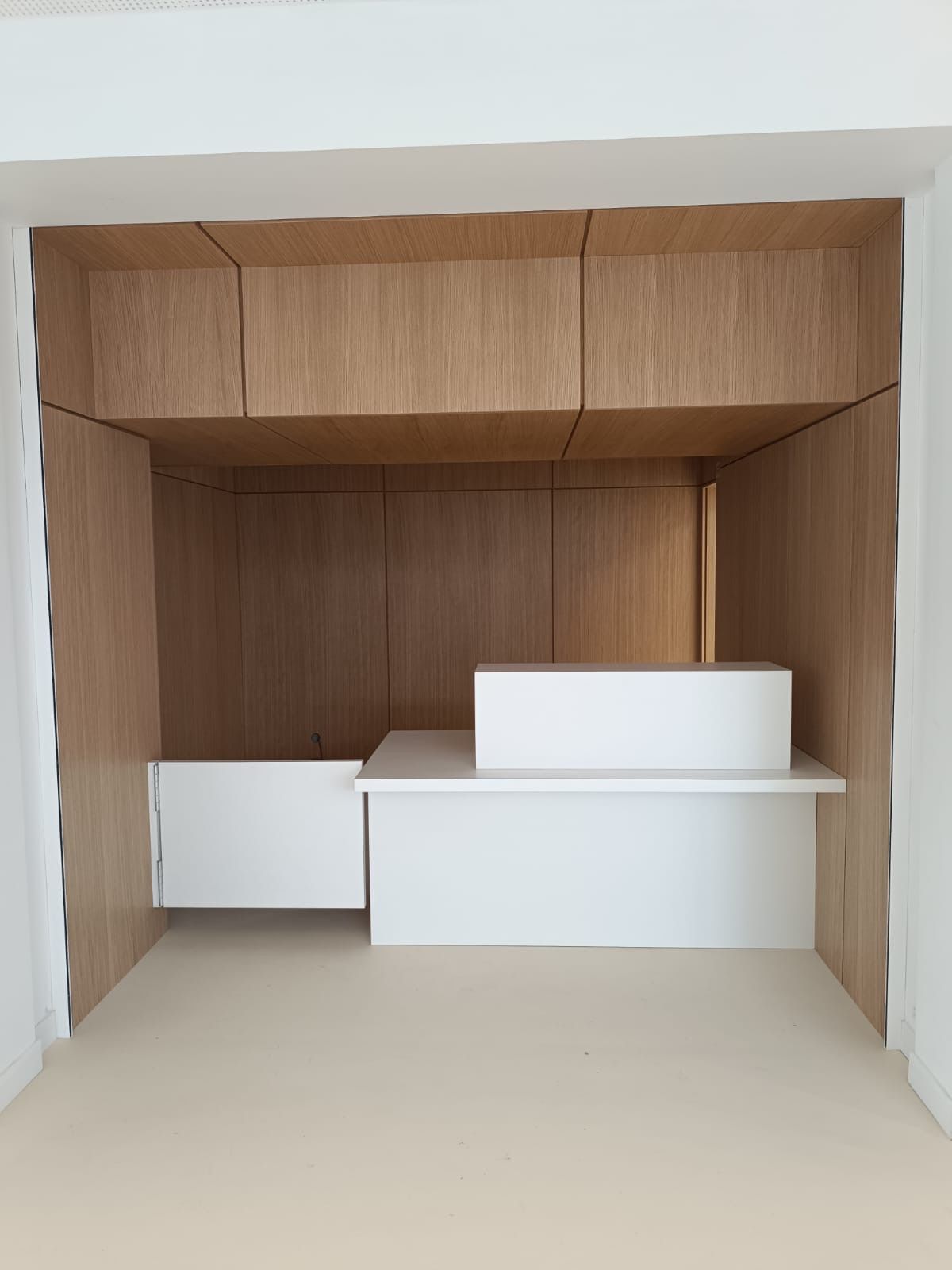 Meubles en bois intégrés avec bureau blanc et tiroirs dans une niche.