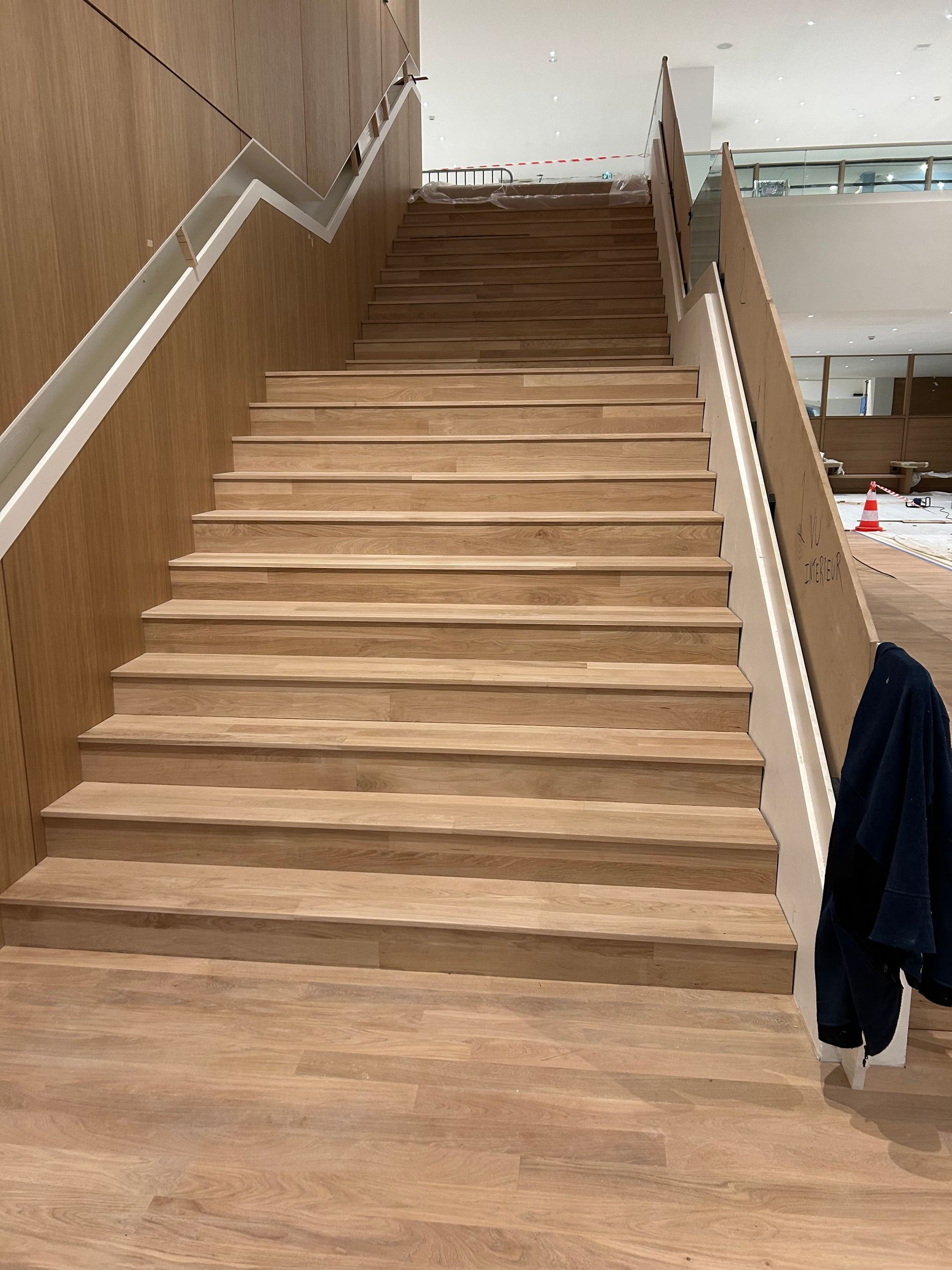 Un escalier en bois aux rampes blanches et aux murs bruns monte.