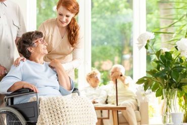 alte Frau im Rollstuhl und junge Pflegerin