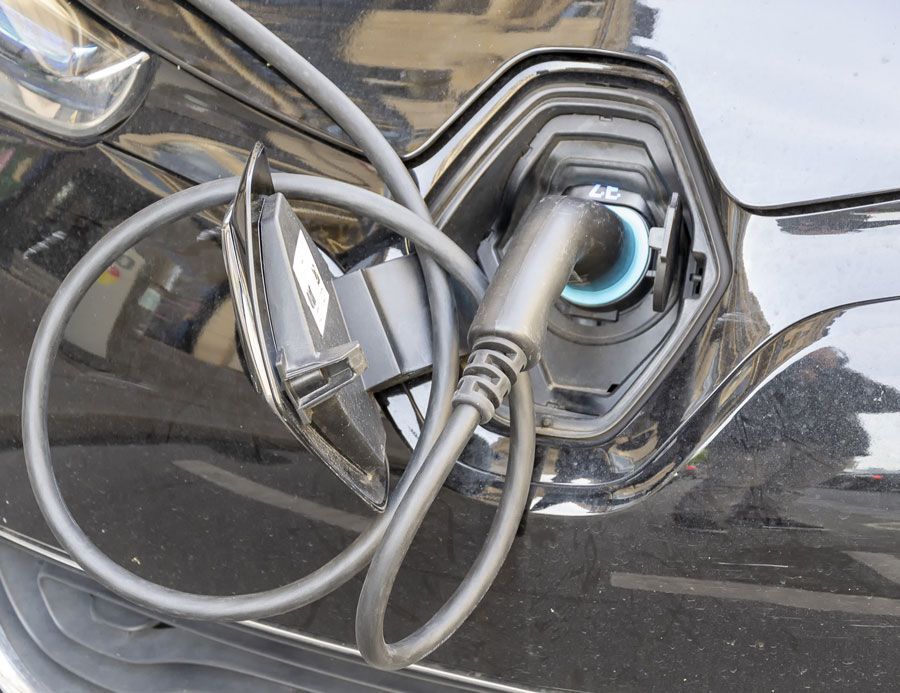 Recharge de voiture électrique, voiture noire, câble de recharge branché, gros plan.