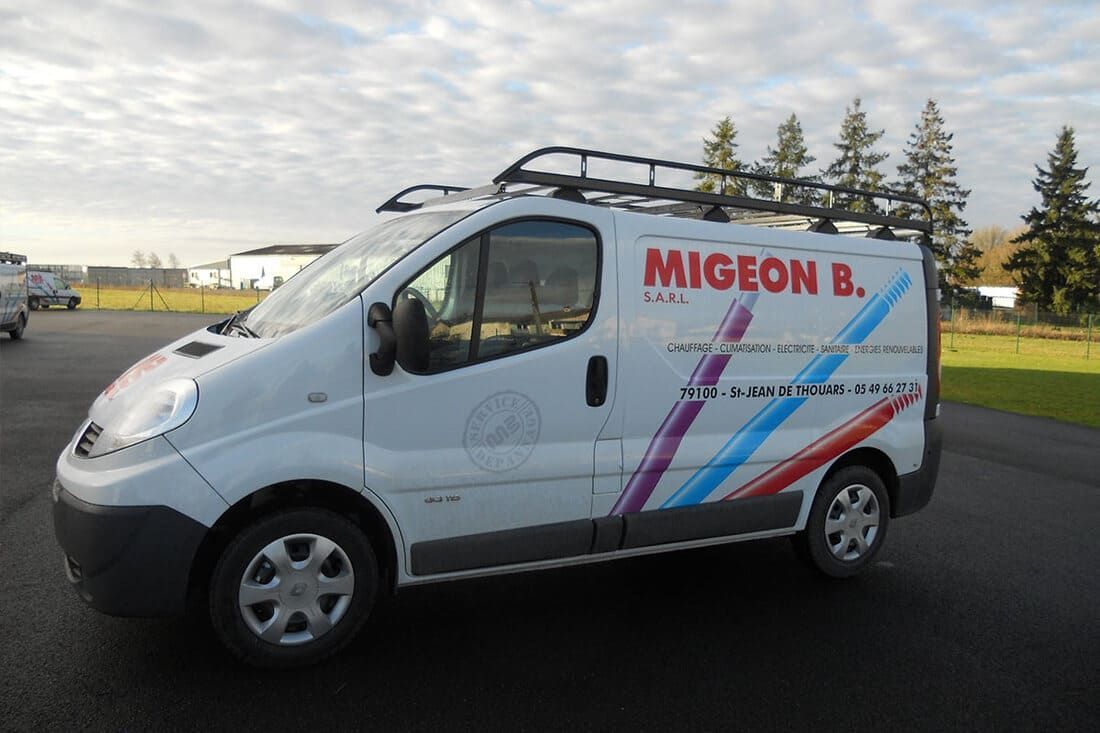 Fourgonnette blanche avec logo MIGEON B. sur le côté, galerie de toit, stationnée à l'extérieur.