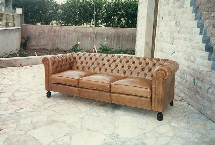 Sofá Chesterfield de couro marrom ao ar livre em um pátio de azulejos.