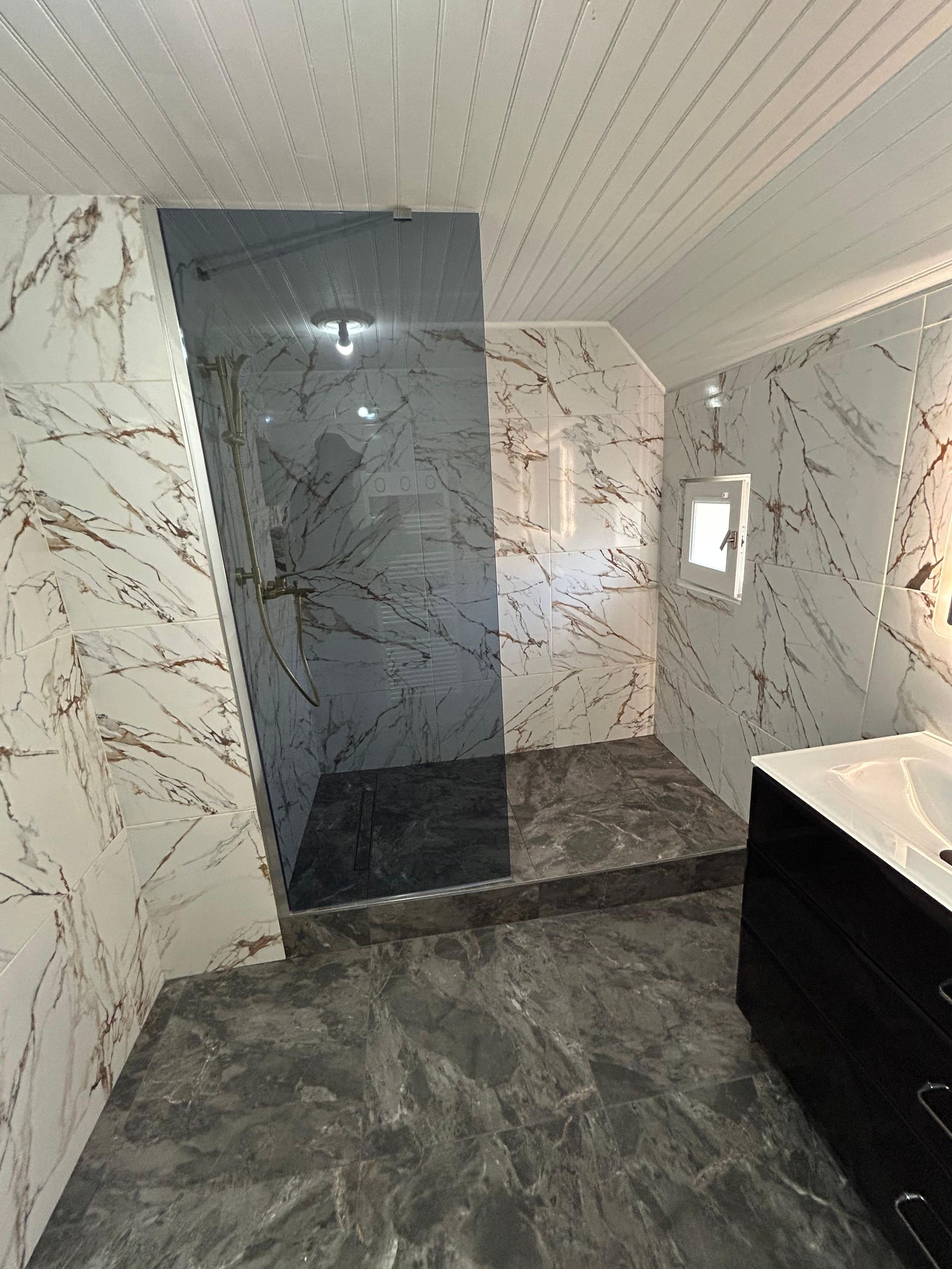 Salle de bain avec murs et sol en marbre, douche à l'italienne et vanité.