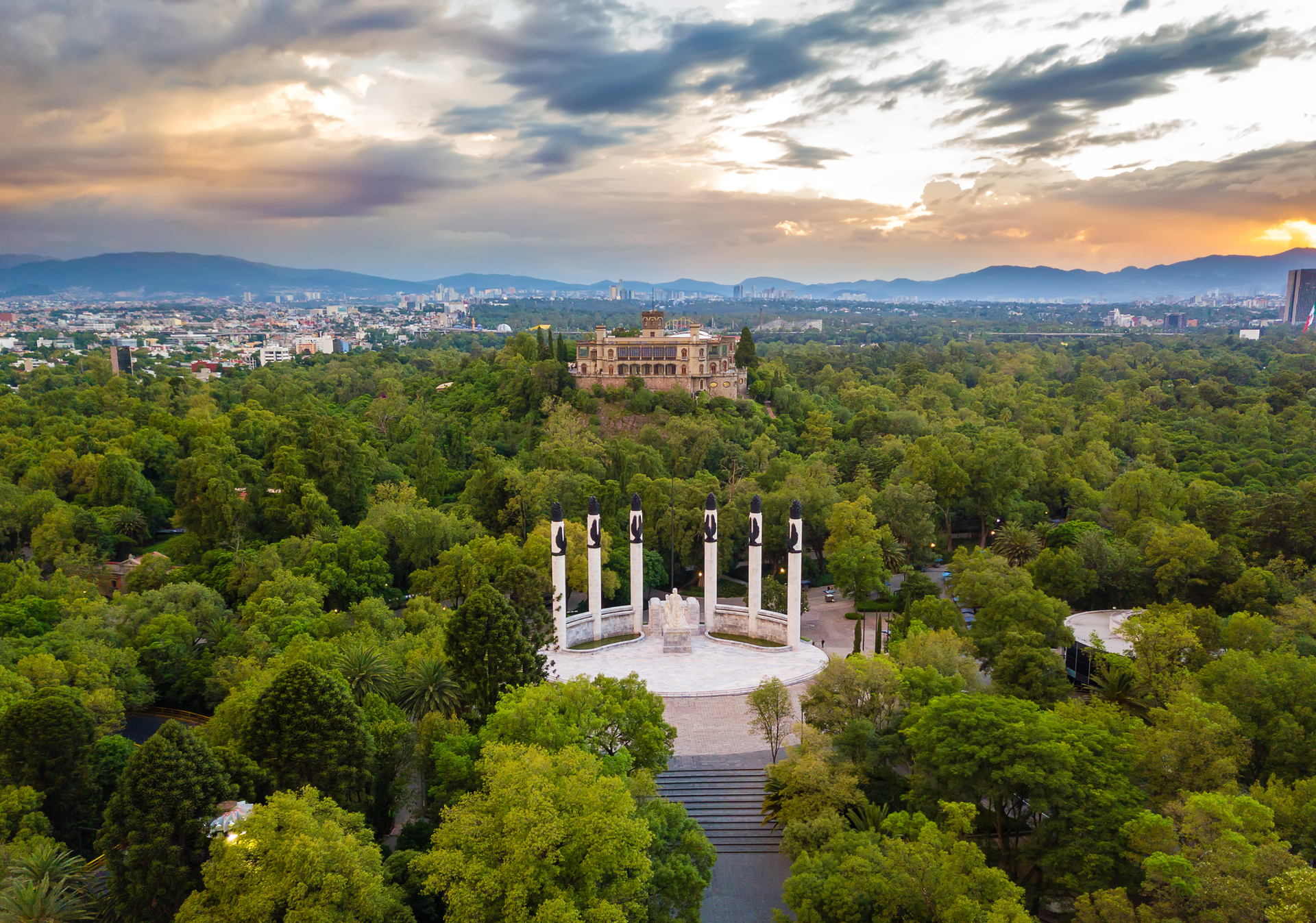 Chapultepec Castle, Mexico City, atop a tree-covered hill with city skyline backdrop.