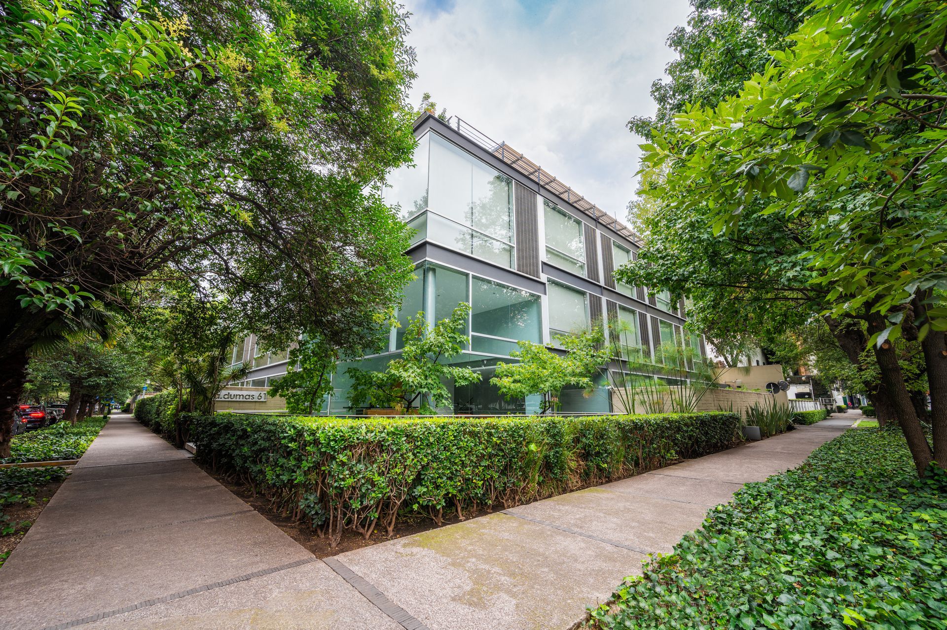 A large building with a lot of windows is surrounded by trees and bushes.