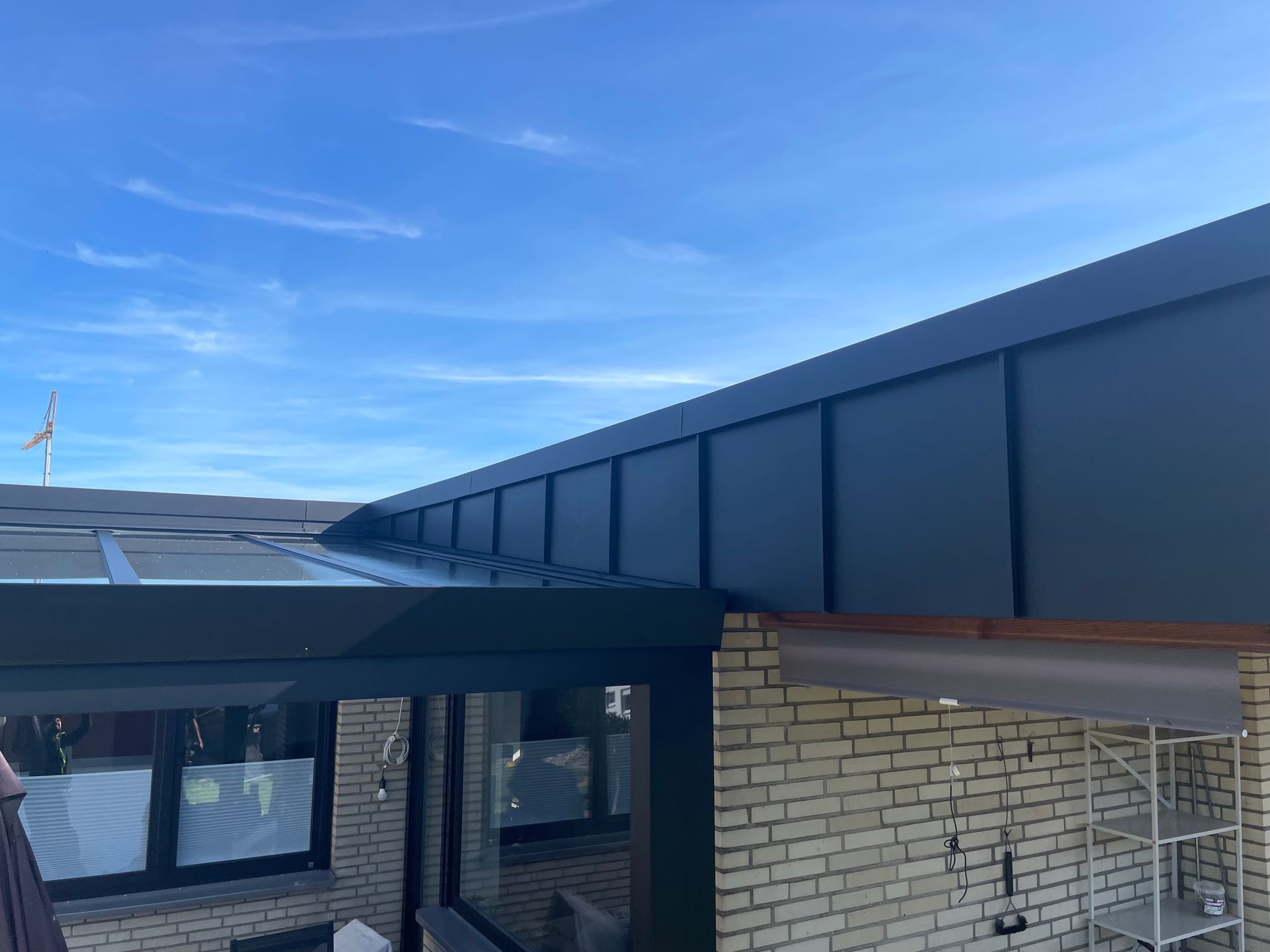 Ein Backsteingebäude mit einem schwarzen Dach und einem blauen Himmel im Hintergrund.