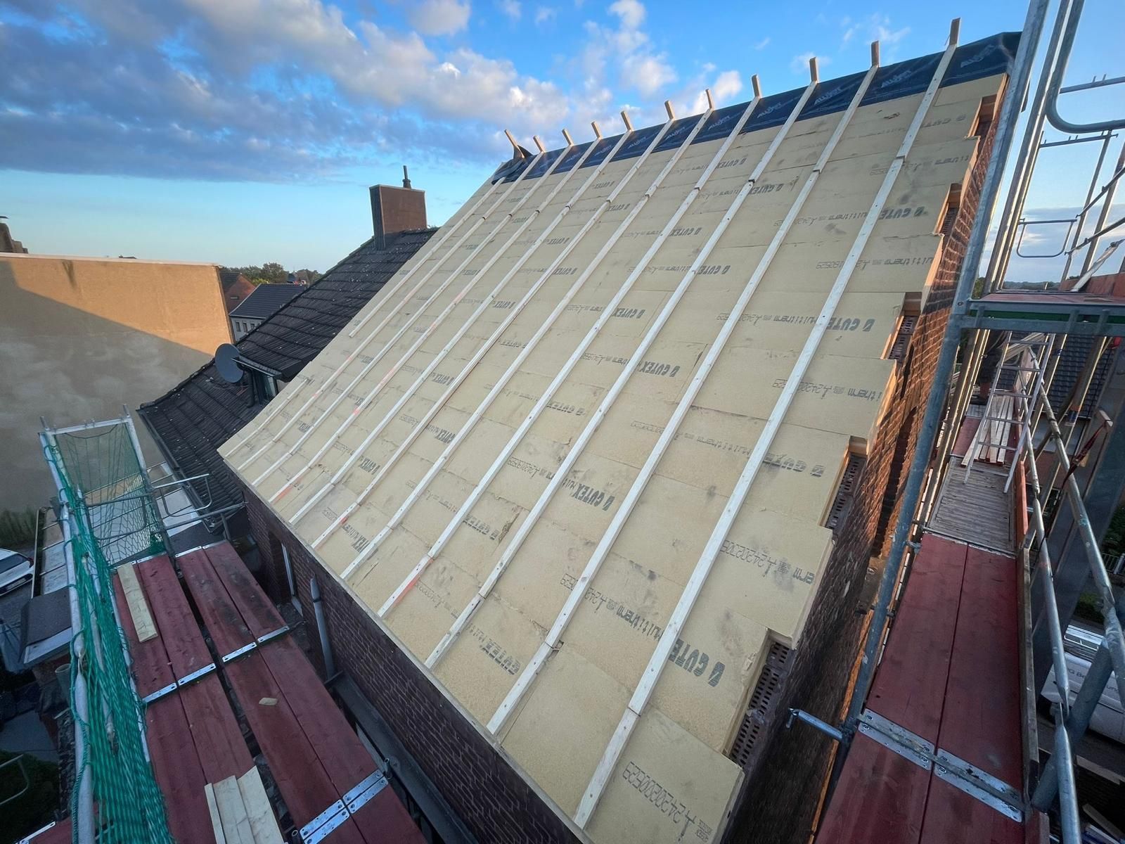 Das Dach eines Gebäudes wird gebaut und ist von einem Gerüst umgeben.