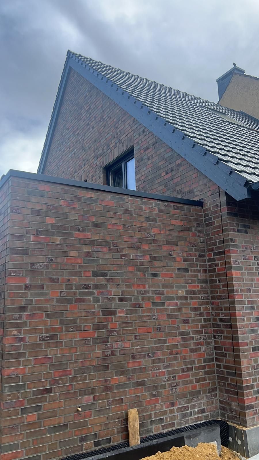 Ein Backsteingebäude mit einem Dach und einem Fenster.