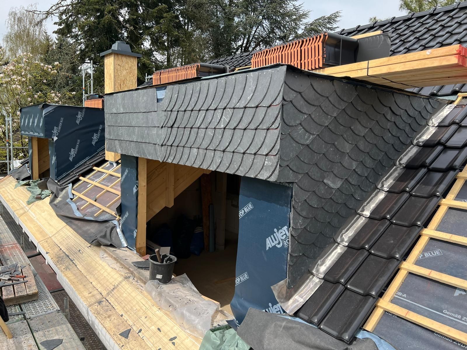 Es wird ein Dach mit Schieferziegeln und ein Schornstein gebaut.