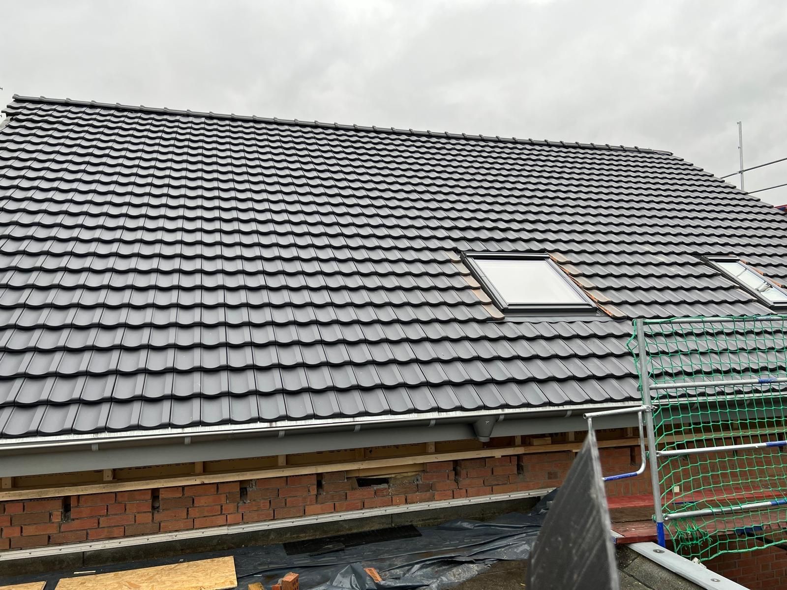 Ein Dach mit vielen Ziegeln und zwei Oberlichtern darauf.