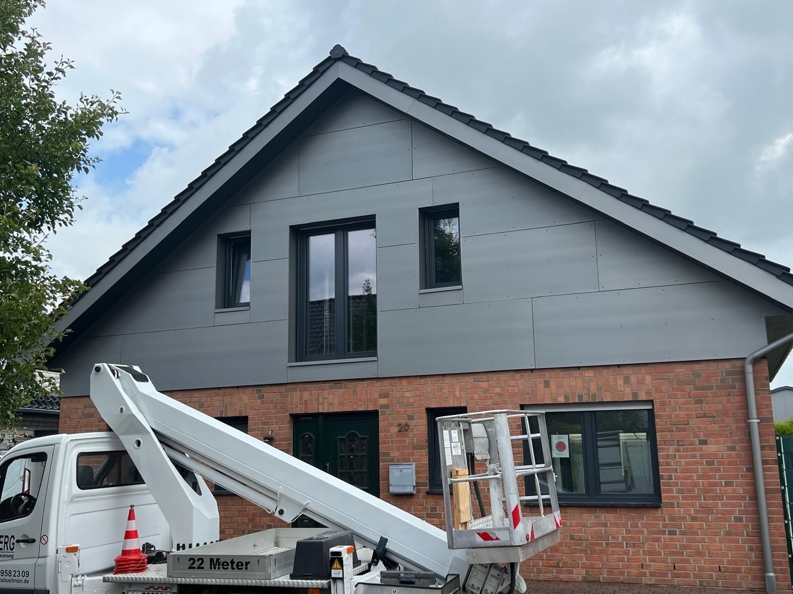 Ein weißer Lastwagen steht vor einem Backsteinhaus.