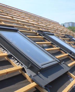 Auf einem Dach wird eine Reihe Oberlichter installiert.