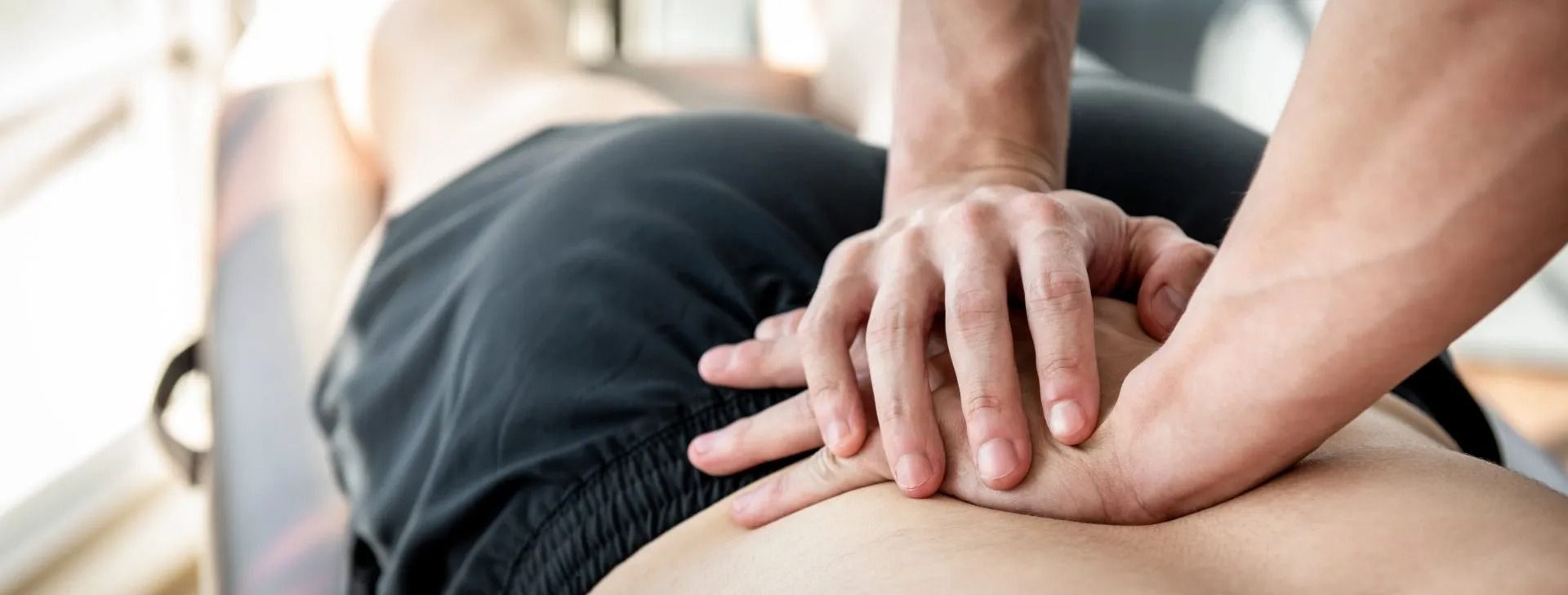 Handen die tijdens een massagebehandeling op de blote rug van een persoon drukken.