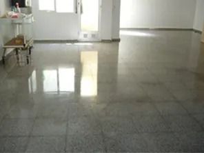 Piso de baldosas grises pulidas que reflejan la luz de las ventanas y la puerta.