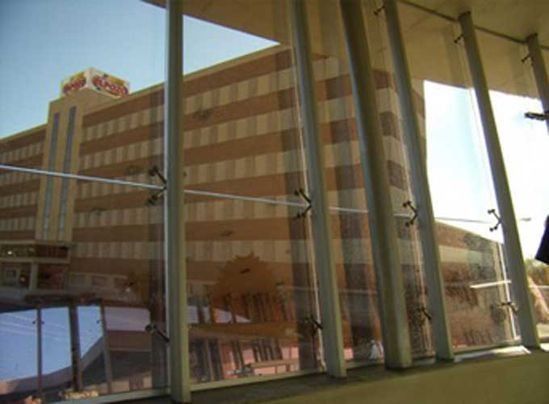 Edificio visto a través de una ventana con divisores verticales; exterior en rayas marrones y blancas.
