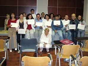 Grupo de personas sosteniendo certificados, sonriendo en un entorno de aula.