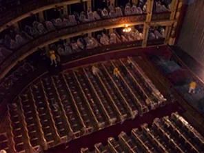 Toma desde un ángulo alto de un auditorio de teatro con filas de asientos y tres trabajadores en los pasillos.