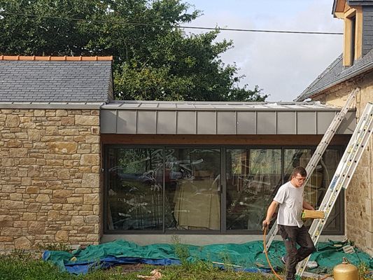 Ouvrier du bâtiment près d'un bâtiment avec des murs en pierre et des fenêtres en verre.