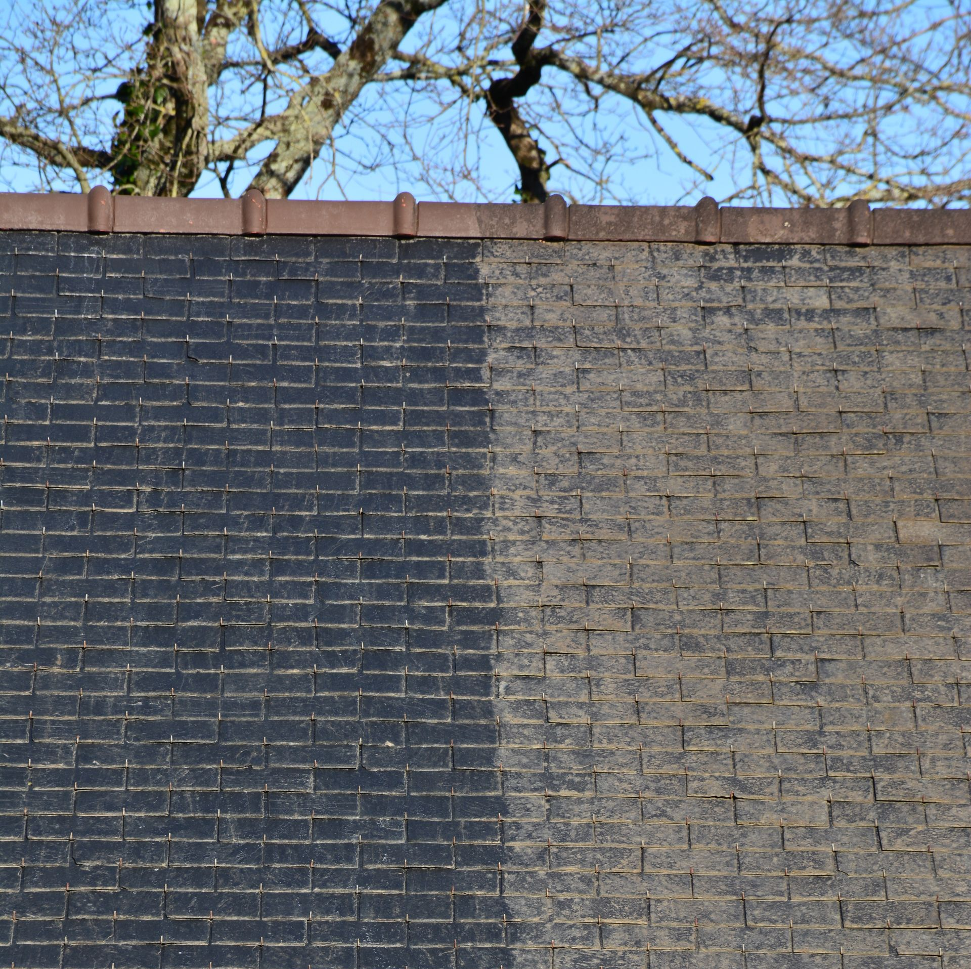 Moitié d'un toit nettoyé, montrant un contraste entre les bardeaux noir et gris sale.