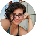 A woman wearing glasses and a green tank top is sitting in a circle.